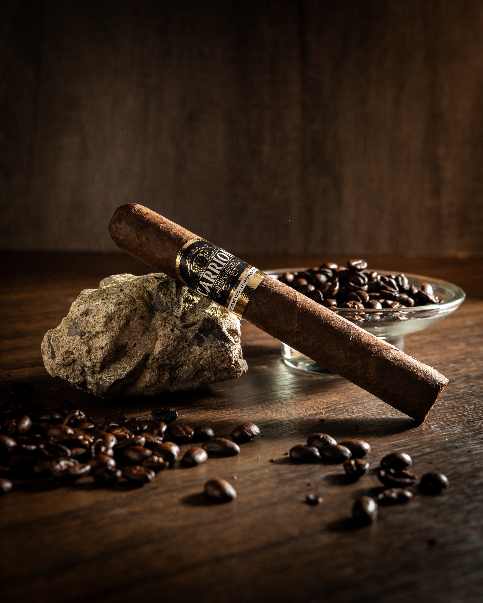 Puro Carrion sobre una piedra, rodeado de granos de café, en una mesa de madera